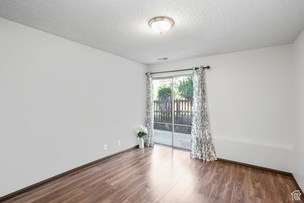 Unfurnished room featuring wood-type flooring and a textured ceiling