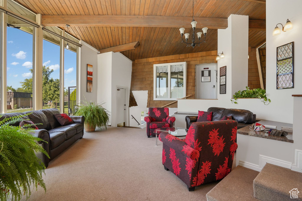 Carpeted living room with beamed ceiling, a chandelier, and wooden ceiling