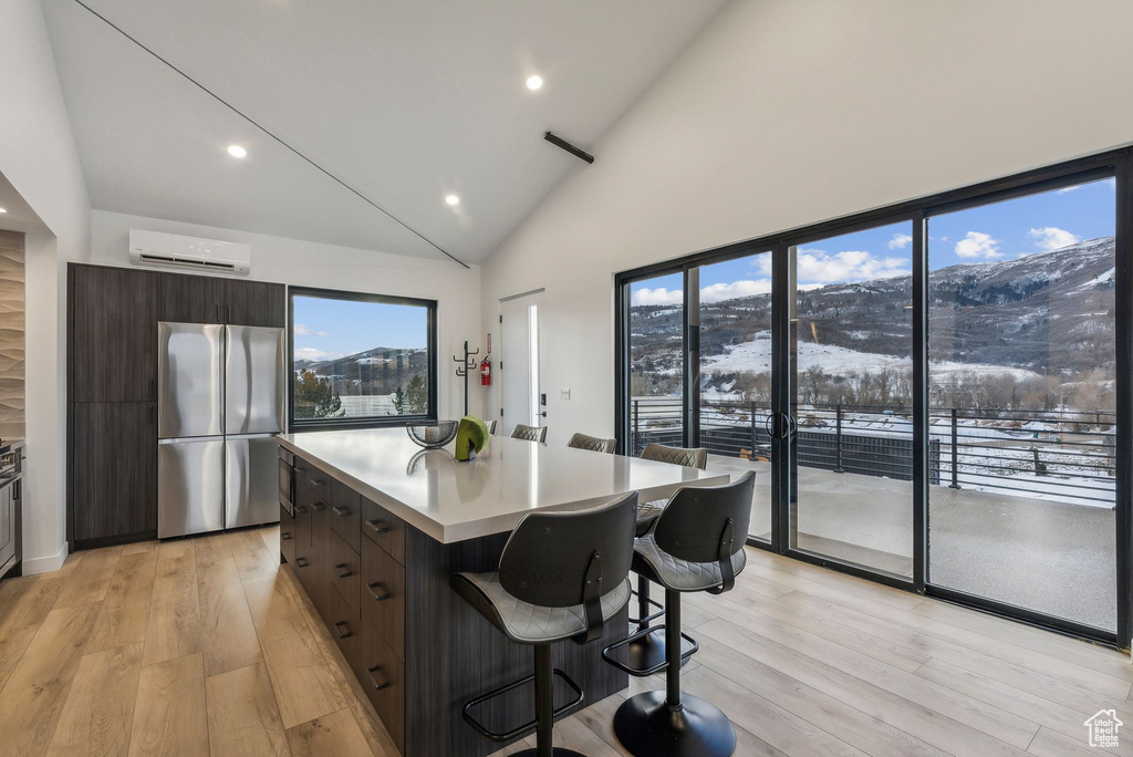 Kitchen with a wall mounted air conditioner, a mountain view, a center island, light hardwood / wood-style floors, and stainless steel refrigerator