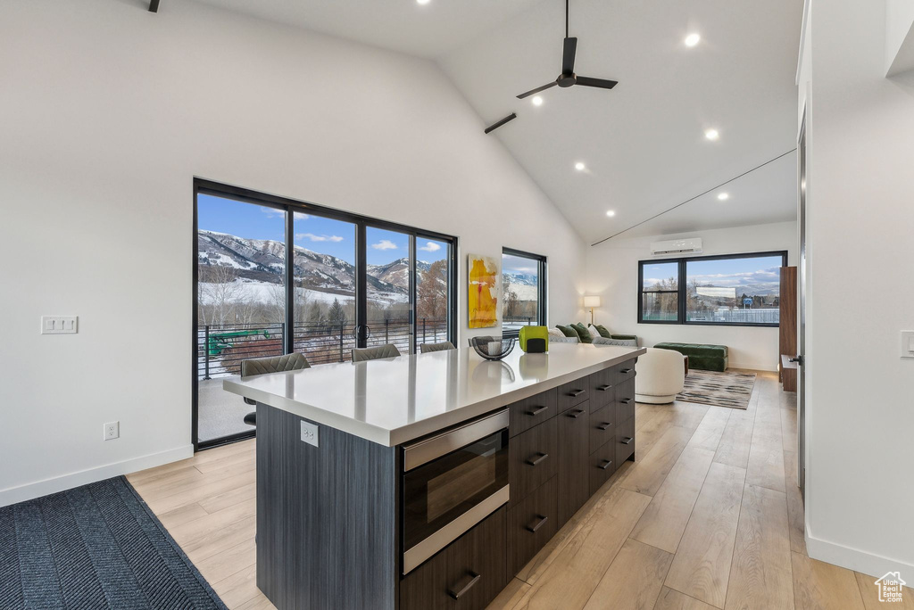 Kitchen featuring a mountain view, stainless steel microwave, high vaulted ceiling, and light hardwood / wood-style floors