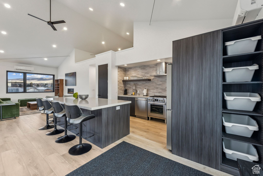 Kitchen with a breakfast bar, appliances with stainless steel finishes, a kitchen island, and lofted ceiling