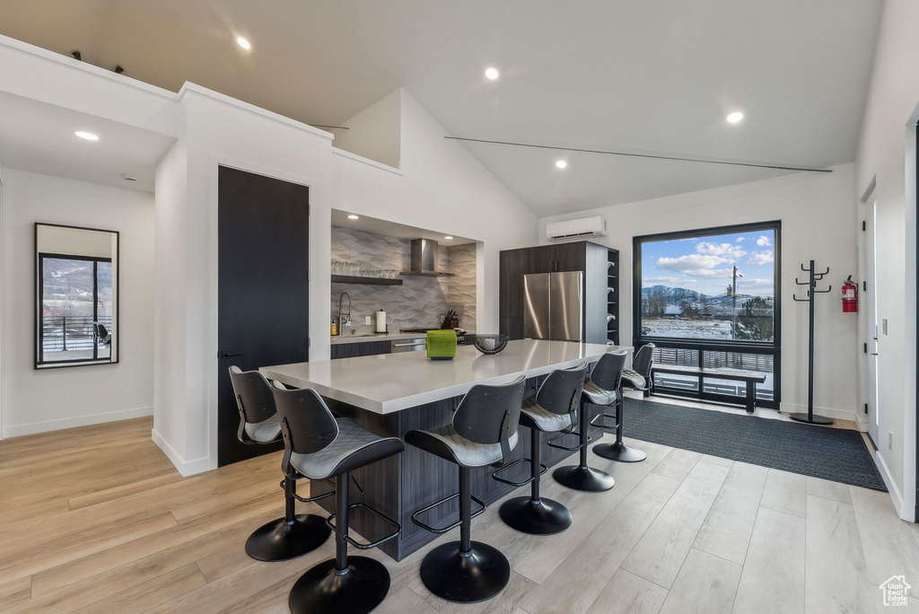 Kitchen with plenty of natural light, light hardwood / wood-style floors, a kitchen breakfast bar, and vaulted ceiling
