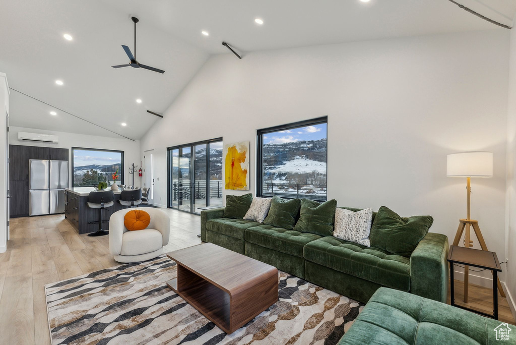 Living room featuring a wall mounted AC, ceiling fan, light hardwood / wood-style flooring, and high vaulted ceiling