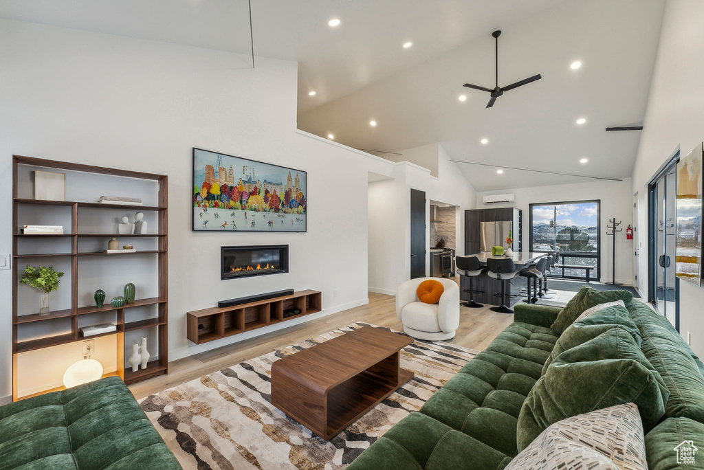 Living room featuring ceiling fan, light hardwood / wood-style floors, high vaulted ceiling, and a wall mounted AC