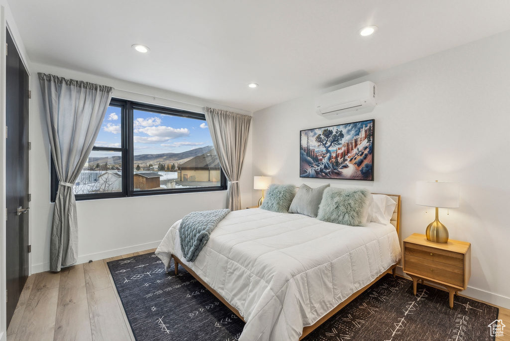 Bedroom featuring a wall mounted air conditioner and hardwood / wood-style flooring