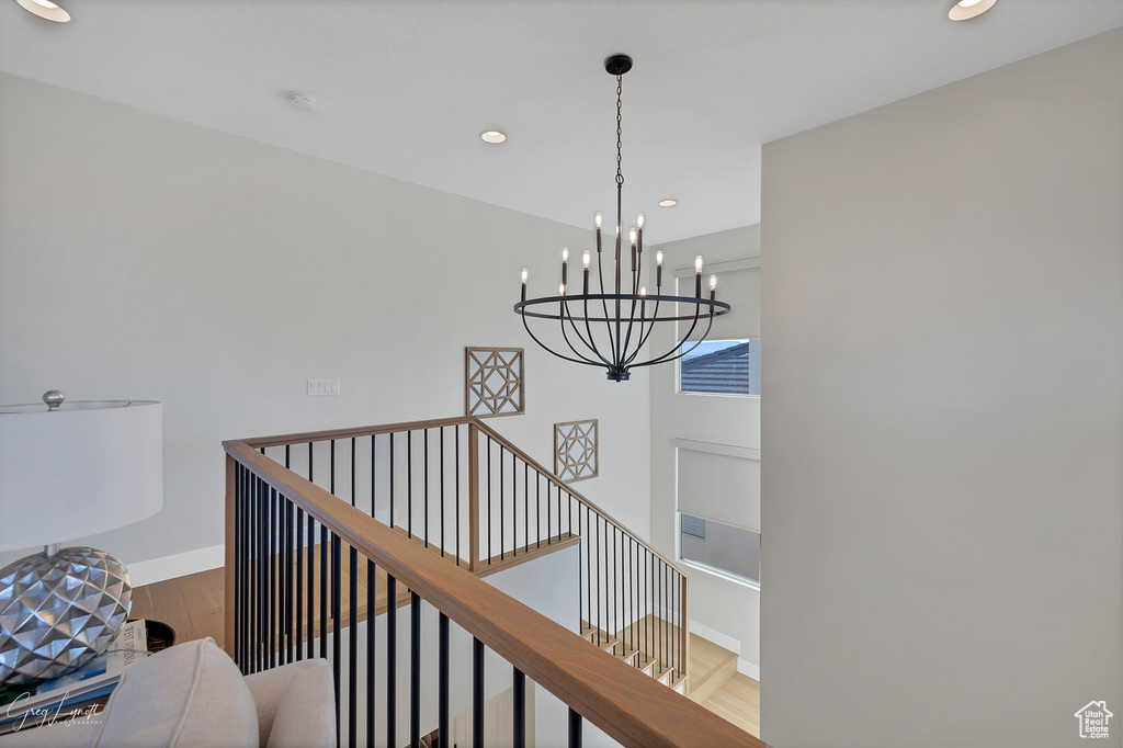 Stairs with wood-type flooring and an inviting chandelier