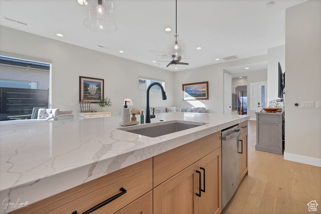 Kitchen with ceiling fan, light stone counters, sink, dishwasher, and light wood-type flooring