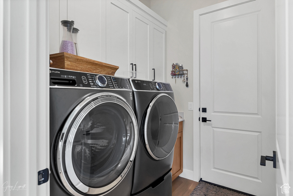 Laundry area featuring dark hardwood / wood-style floors, independent washer and dryer, and cabinets