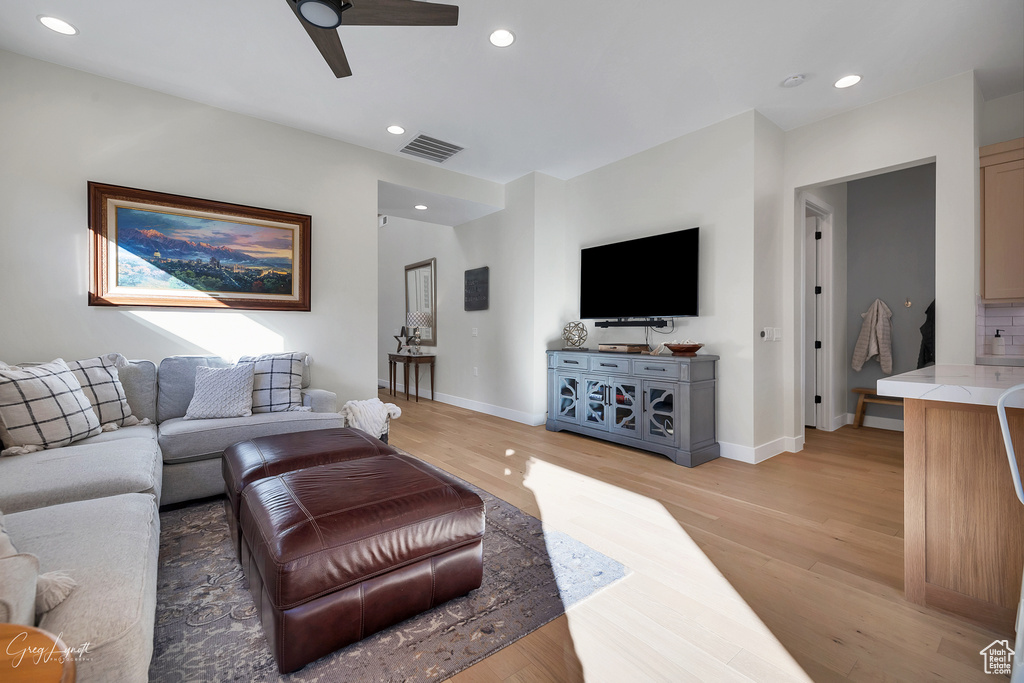 Living room with light hardwood / wood-style floors and ceiling fan