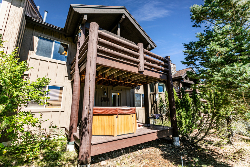 Rear view of house featuring a hot tub and a wooden deck