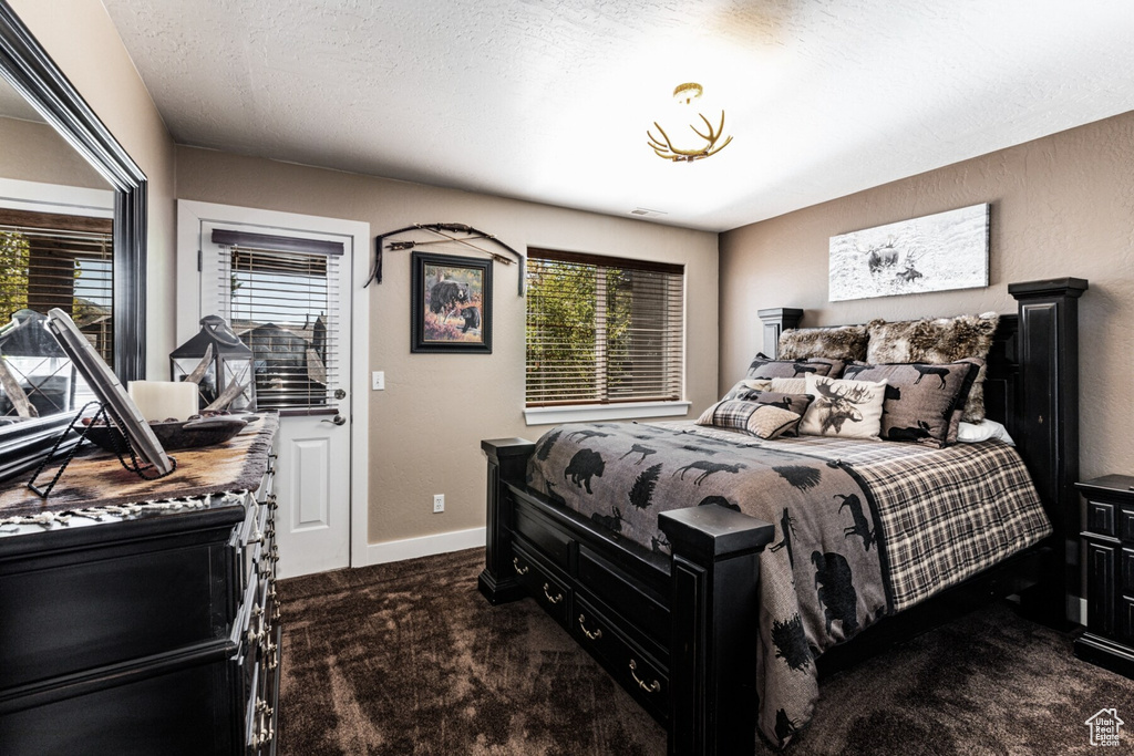 Carpeted bedroom featuring a textured ceiling and multiple windows