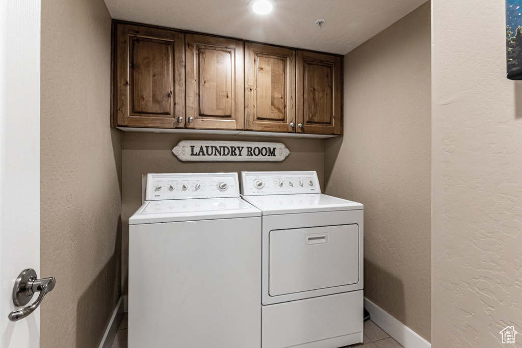 Laundry room with cabinets, light tile patterned floors, and washer and dryer