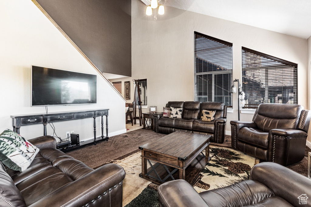 Carpeted living room featuring ceiling fan and a towering ceiling