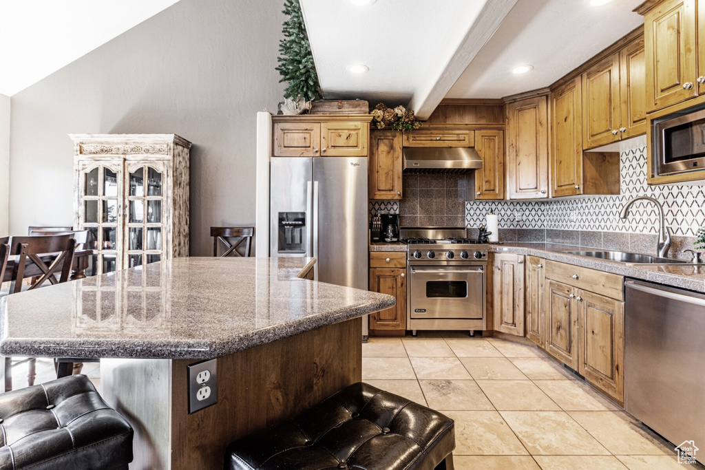 Kitchen featuring light tile patterned flooring, sink, a kitchen island, stainless steel appliances, and backsplash