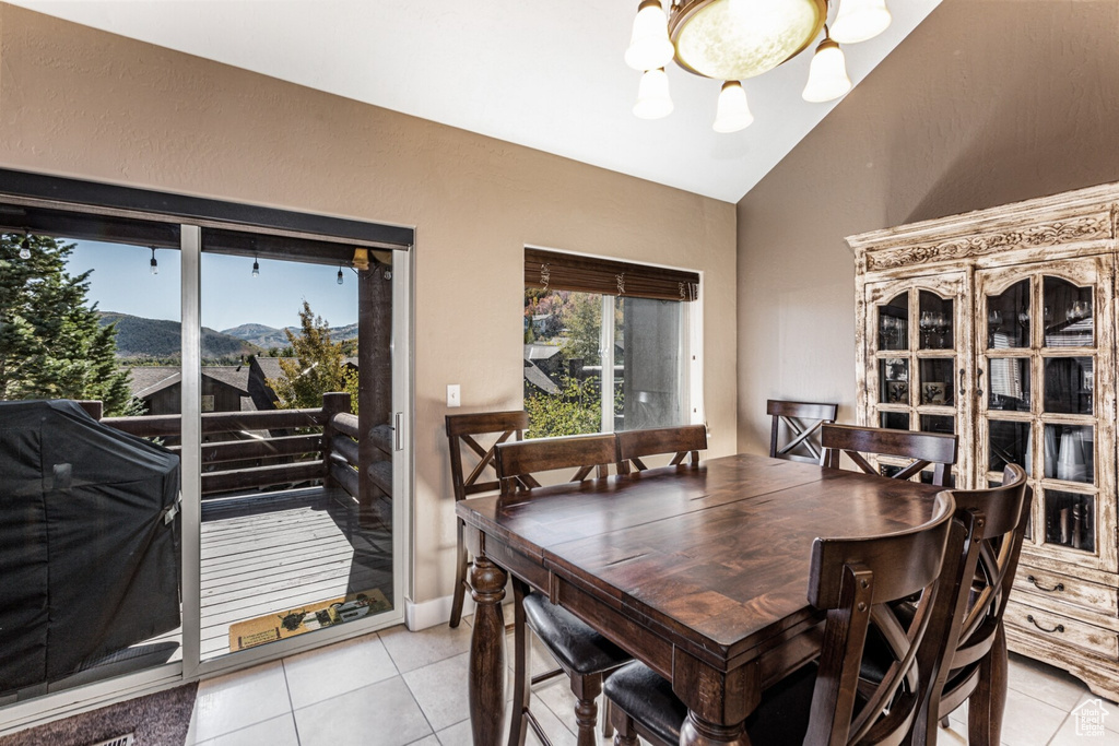 Dining room with light tile patterned flooring, vaulted ceiling, a chandelier, and a mountain view