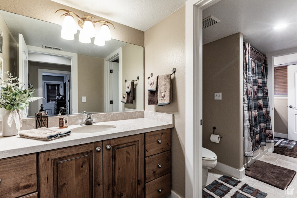 Bathroom with vanity, a textured ceiling, tile patterned flooring, a shower with shower curtain, and toilet