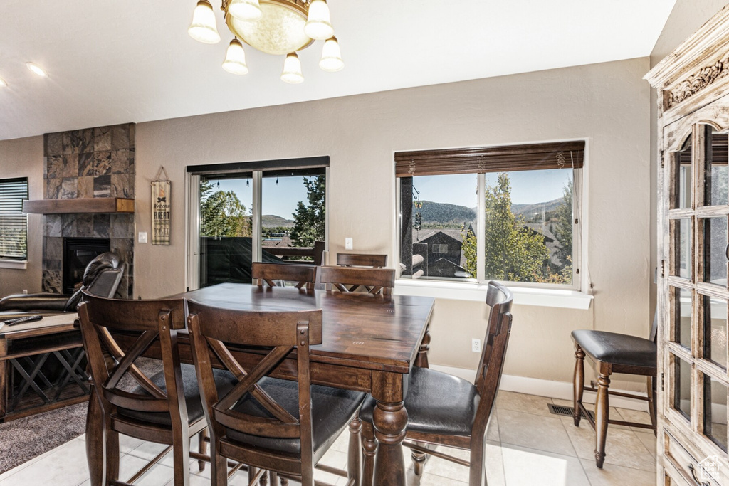 Dining room featuring a mountain view, a notable chandelier, light tile patterned floors, and a large fireplace