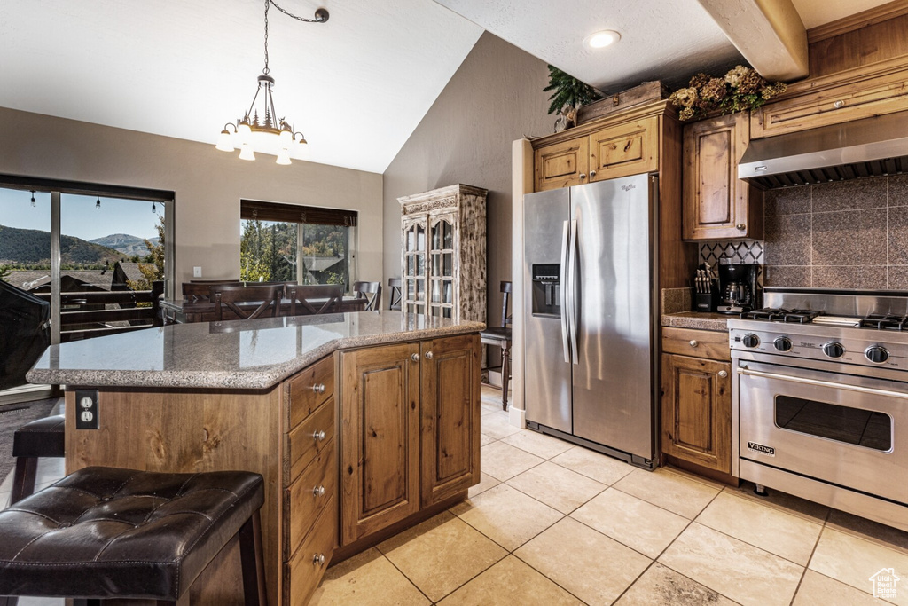 Kitchen featuring stainless steel appliances, light tile patterned floors, hanging light fixtures, and a kitchen island