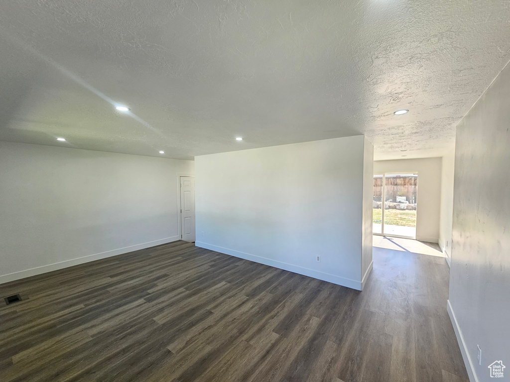 Empty room featuring a textured ceiling and dark hardwood / wood-style flooring