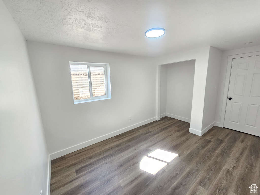 Unfurnished bedroom featuring a textured ceiling, a closet, and dark hardwood / wood-style flooring