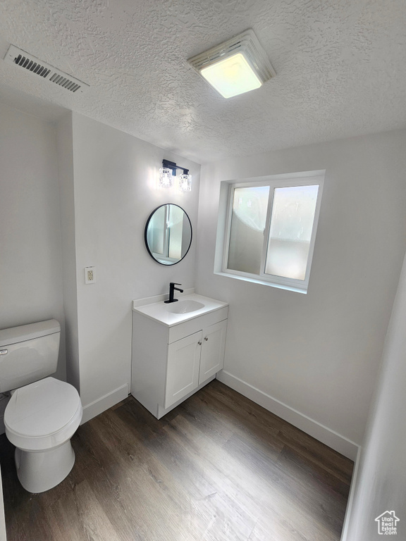 Bathroom featuring vanity, toilet, a textured ceiling, and hardwood / wood-style flooring