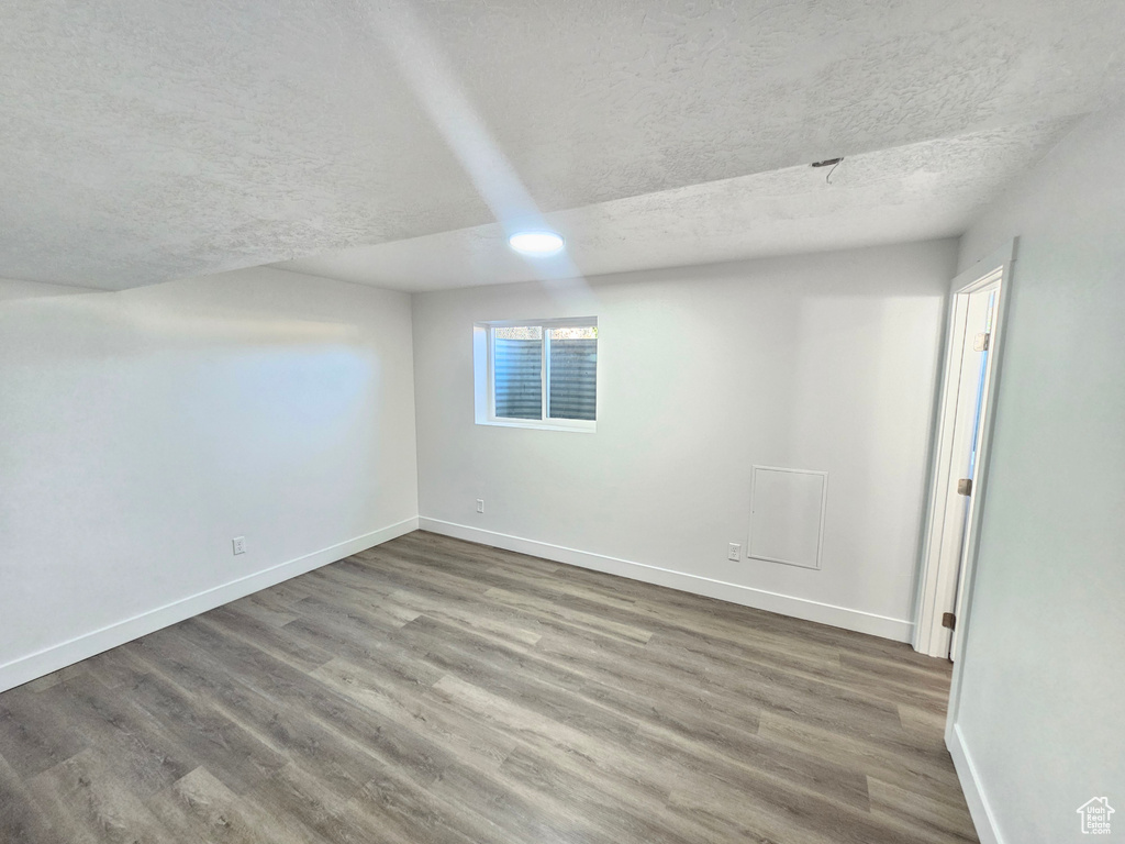 Unfurnished room with a textured ceiling and hardwood / wood-style flooring