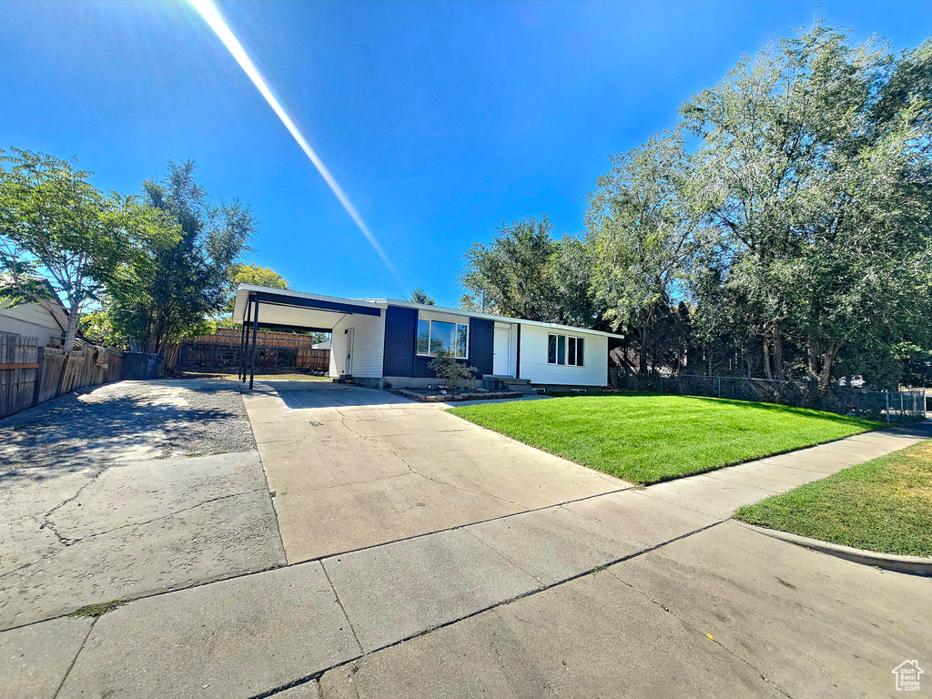 Ranch-style home featuring a front lawn and a carport