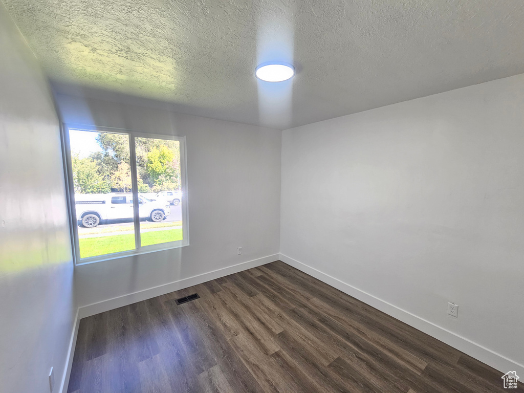 Unfurnished room featuring a textured ceiling and dark wood-type flooring