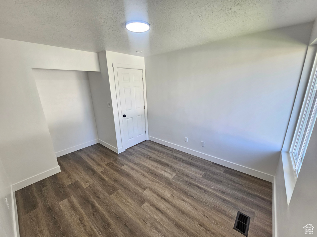 Unfurnished bedroom with a textured ceiling and dark hardwood / wood-style floors