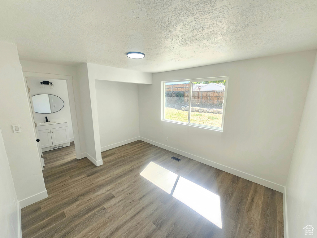 Spare room featuring a textured ceiling, sink, and dark wood-type flooring