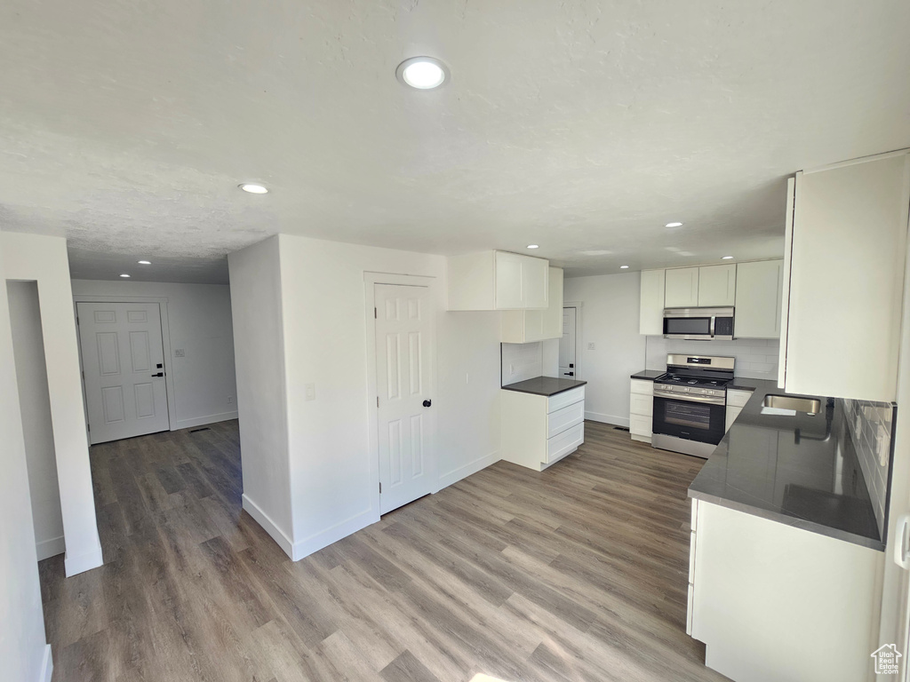 Kitchen featuring white cabinets, stainless steel appliances, and light hardwood / wood-style floors