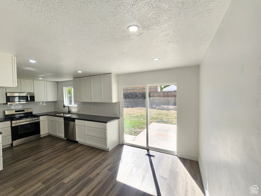 Kitchen featuring white cabinets, sink, a textured ceiling, stainless steel appliances, and dark hardwood / wood-style floors