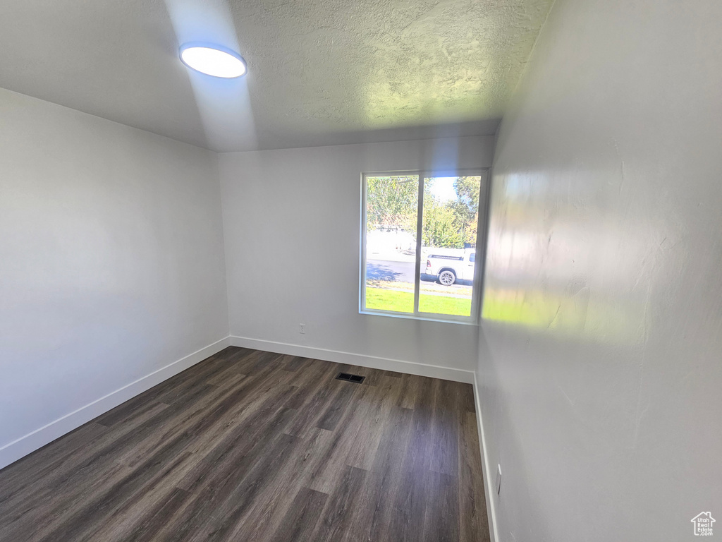 Spare room featuring a textured ceiling and dark wood-type flooring