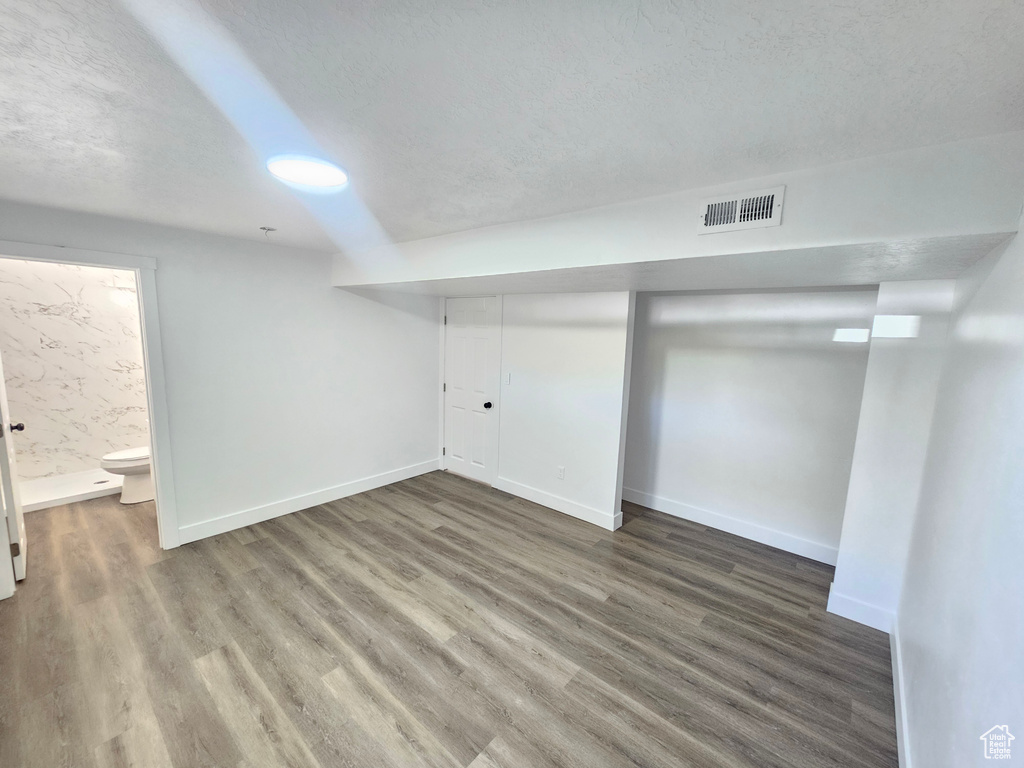 Basement with a textured ceiling and hardwood / wood-style floors