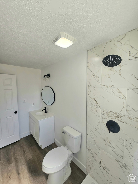 Bathroom with a tile shower, wood-type flooring, a textured ceiling, and vanity