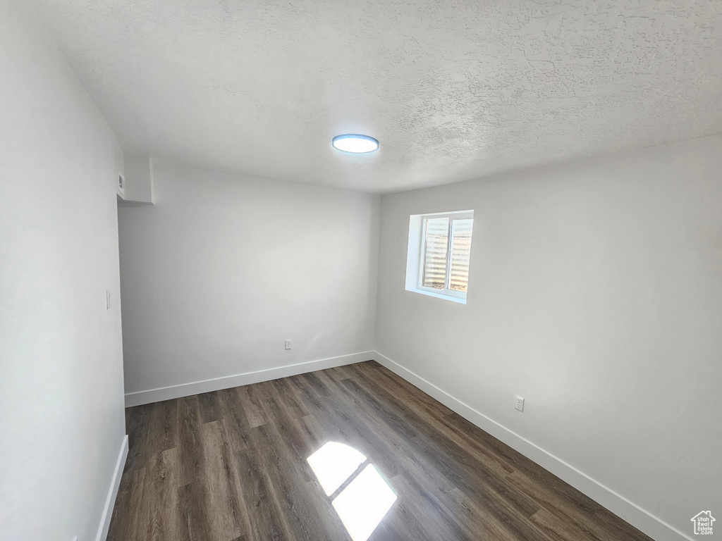 Unfurnished room featuring a textured ceiling and dark hardwood / wood-style flooring