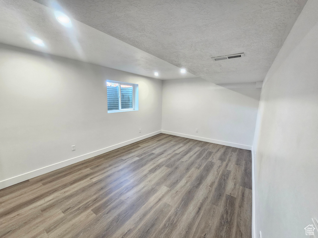 Basement with a textured ceiling and hardwood / wood-style flooring