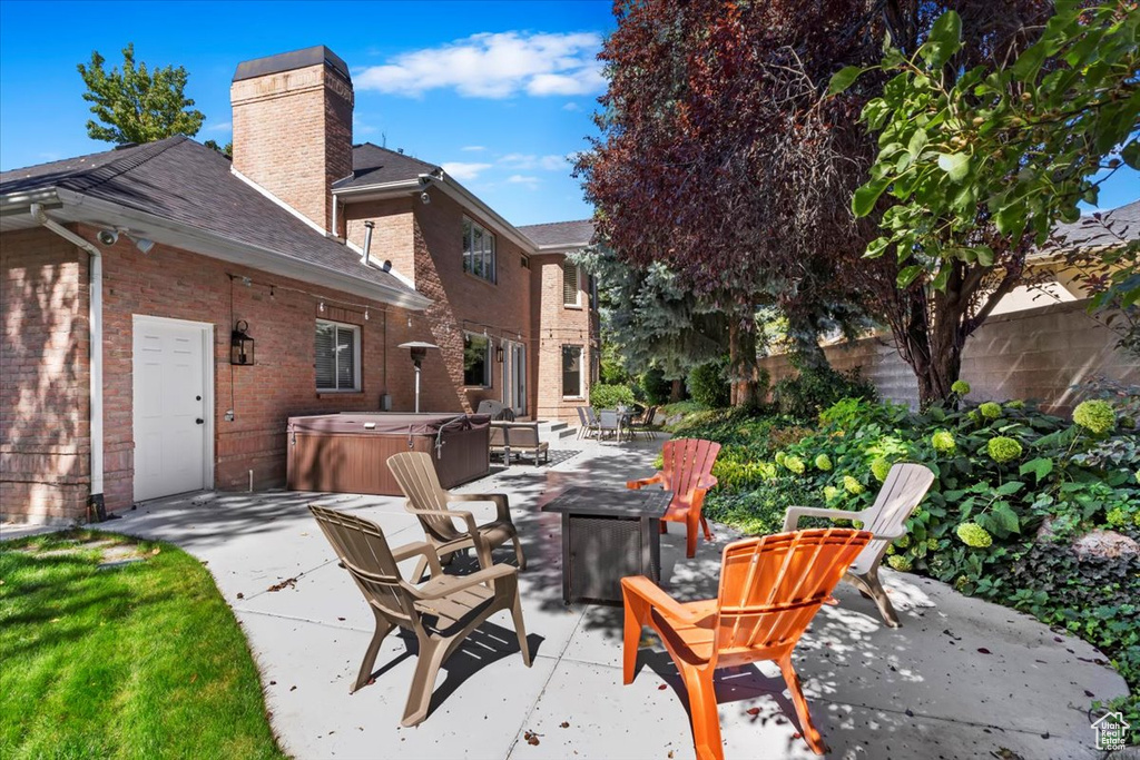 View of patio featuring a hot tub and an outdoor fire pit