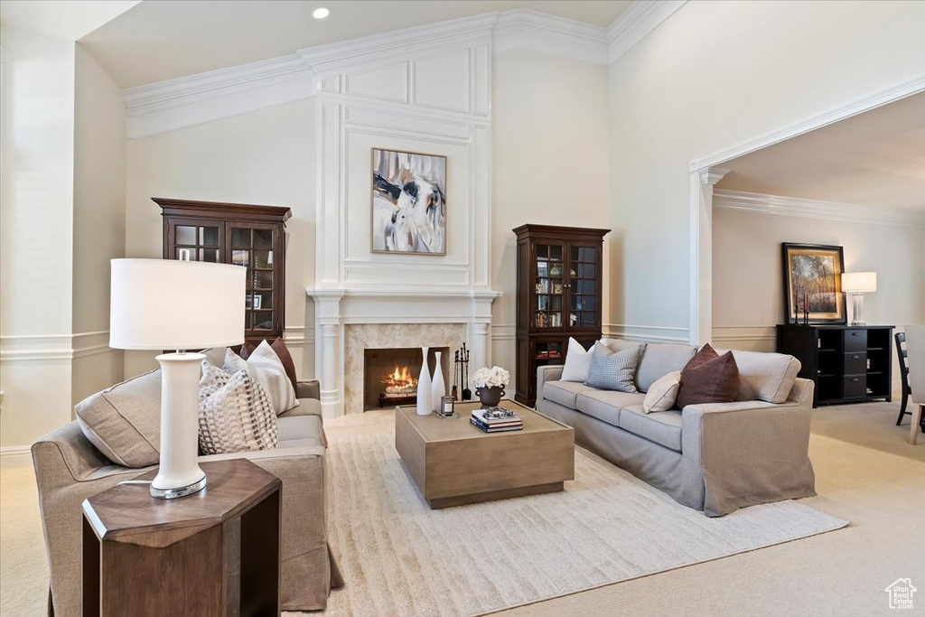 Living room with light colored carpet, a premium fireplace, a high ceiling, and crown molding