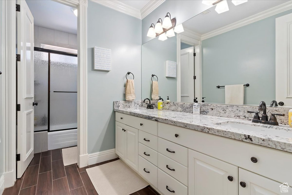 Bathroom featuring vanity, crown molding, and combined bath / shower with glass door