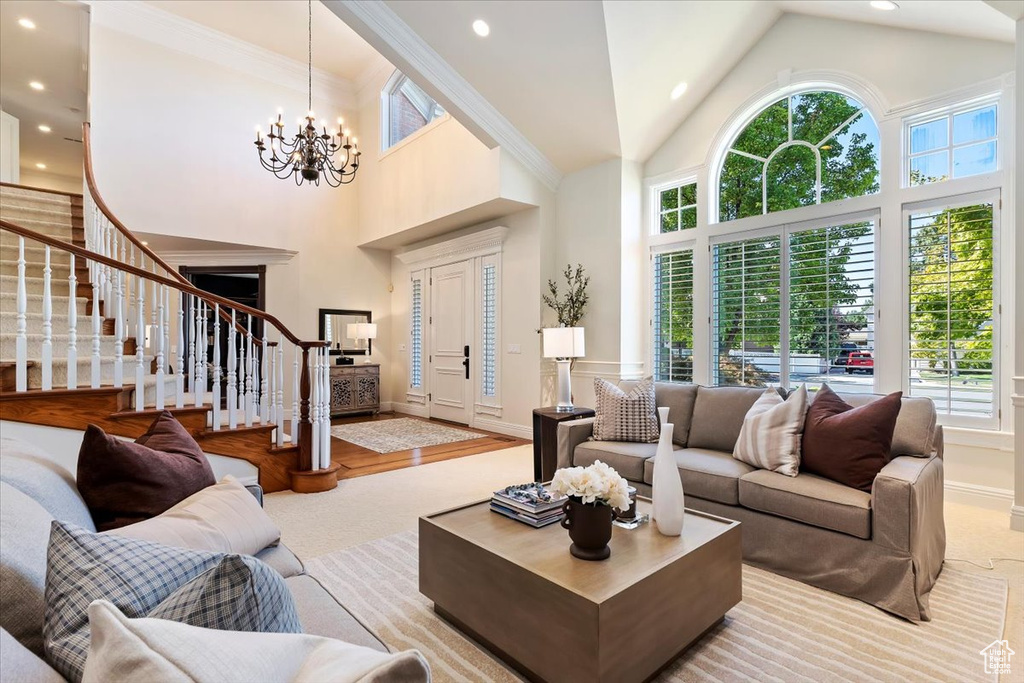 Living room with crown molding, light hardwood / wood-style floors, an inviting chandelier, and high vaulted ceiling