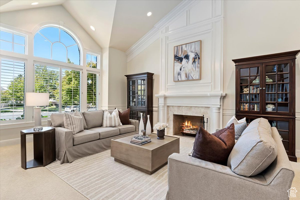 Carpeted living room featuring a fireplace and high vaulted ceiling