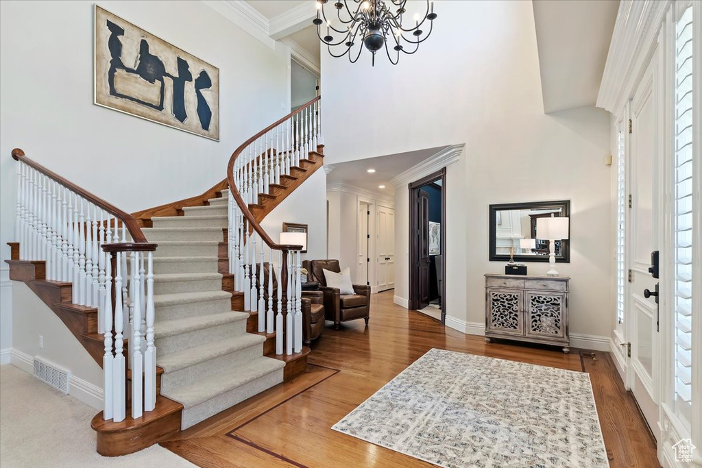 Entrance foyer featuring a healthy amount of sunlight, ornamental molding, an inviting chandelier, and hardwood / wood-style floors