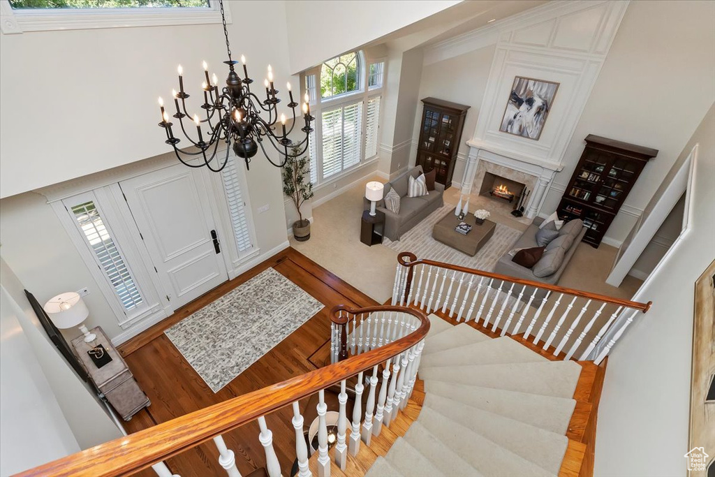 Foyer entrance with hardwood / wood-style floors, a premium fireplace, a high ceiling, and a chandelier