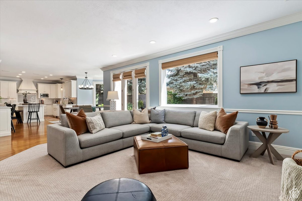 Living room with a notable chandelier, light hardwood / wood-style flooring, and crown molding