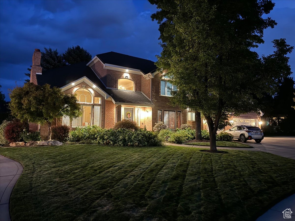 View of front of property with a garage and a yard