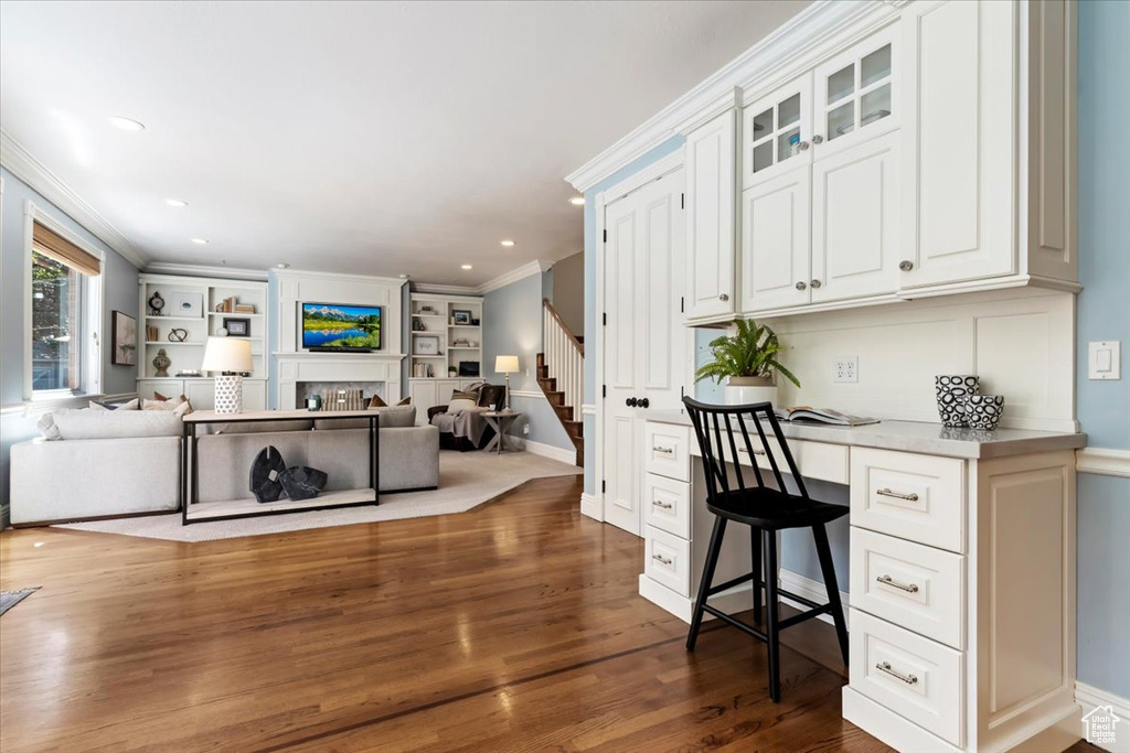 Office area featuring built in desk, dark wood-type flooring, and crown molding