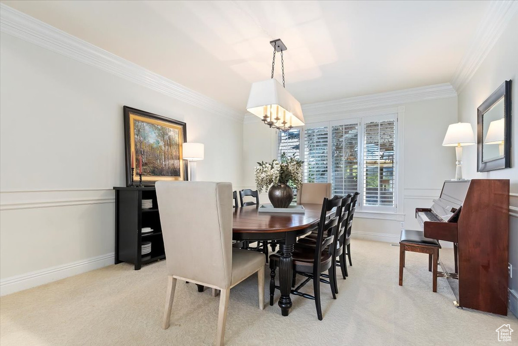 Carpeted dining area with a chandelier and crown molding