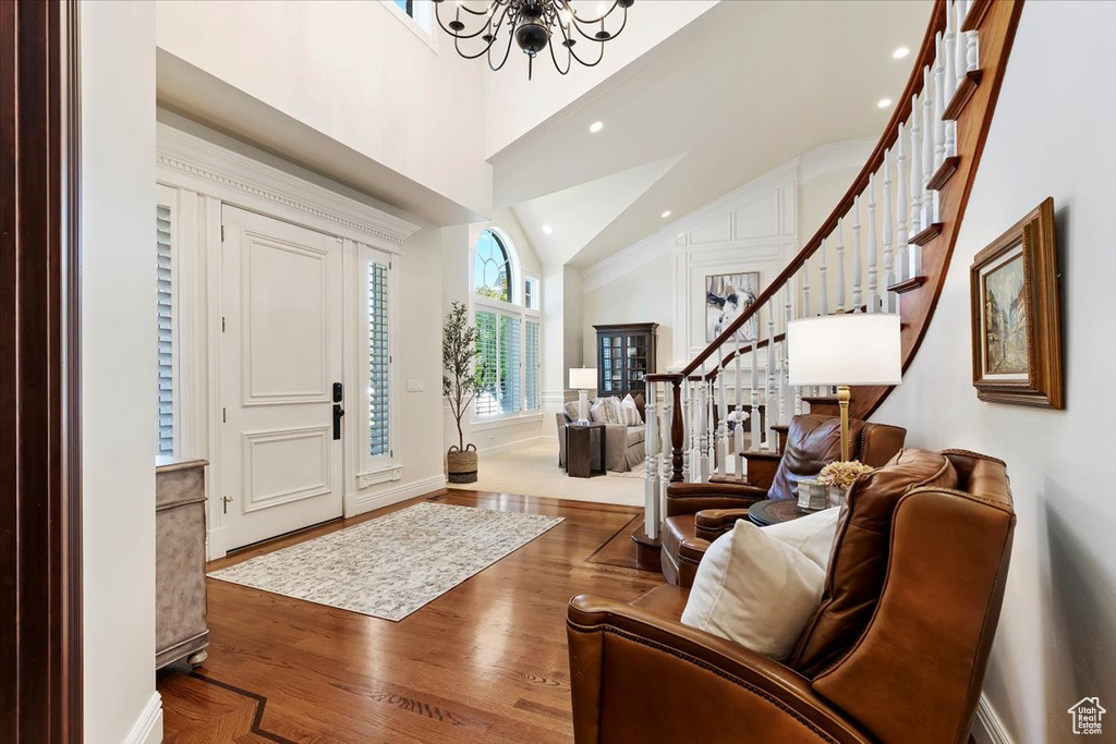 Entrance foyer featuring an inviting chandelier, hardwood / wood-style floors, and high vaulted ceiling