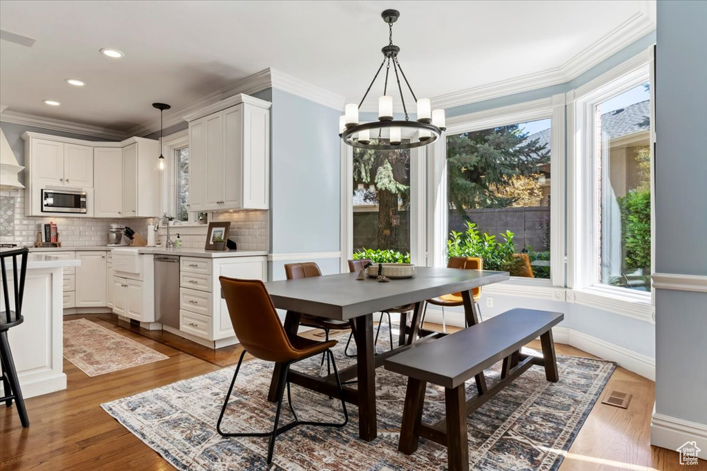 Dining area featuring crown molding, light hardwood / wood-style floors, and a chandelier